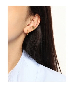 Détail macro d'une manchette d'oreille dorée texturée et d'un anneau minimaliste