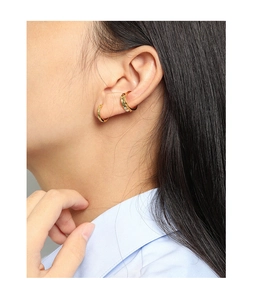 Détail d'une boucle d'oreille créole dorée minimaliste et d'un faux piercing d'oreille
