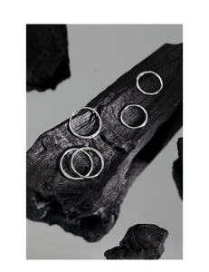 Détail de bagues en argent 925 avec texture martelée irrégulière sur un support de charbon
