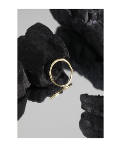 Vue détaillée d'une bague dorée texturée sur charbon avec reflet miroir élégant