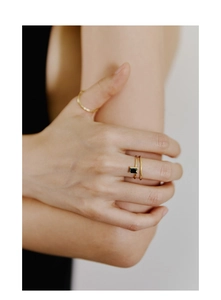 Détail d'une bague minimaliste en or sertie d'une pierre d'onyx noire rectangulaire