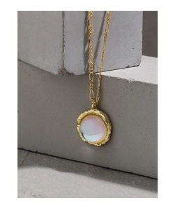 Detailed close-up of golden necklace with moonstone pendant and hammered metal texture
