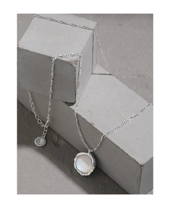 Macro view of silver S925 necklace with mother of pearl pendant on concrete block