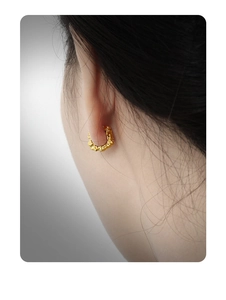 Close-up of golden irregular lava texture hoop earring with artistic molten silver design