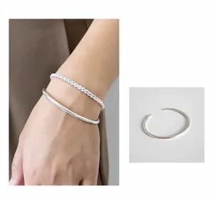 Nahaufnahme von minimalistischem Sterling-Silber-Armreif und gedrehtem Kettenarmband
