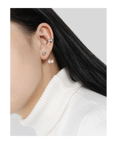 Macro-opname van een minimalistische zilveren oorknopje en drielaagse ear cuff set