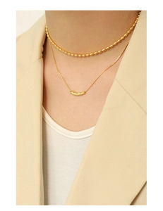 Nahaufnahme der geschichteten goldenen Schlangenkette und Perlenketten mit Blazer