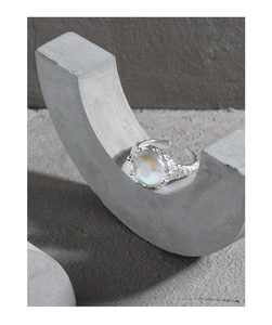 Detail of S925 silver ring with irregular rock texture and oval moonstone on grey base