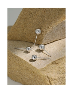 Macro-opname van minimalistische S925 zilveren bolletjes oorbellen op natuursteen