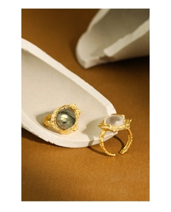 Macro detail of gold S925 silver rings with white crystal and organic lava texture