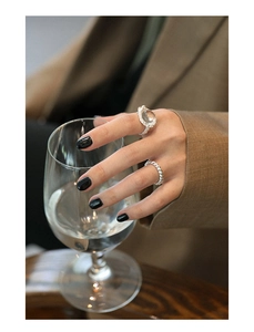 Detail of S925 silver rings with white crystal stone on model's hand with glass