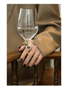 Close-up of retro emerald gemstone ring and textured wavy bands worn by a model