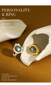 Artistic detail of adjustable silver and gold rings with textured lava surface and labradorite