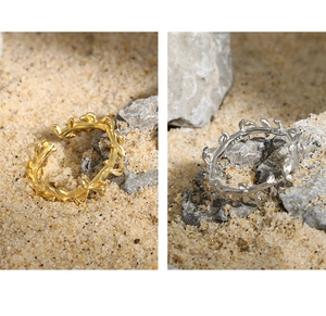 Detail van olijftak ringen in goud en zilver op een natuurlijke zand achtergrond