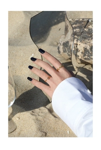 Detail van minimalistische gouden golvende en gedraaide ringen om vingers van een model