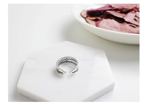 Detailed macro shot of vintage S925 sterling silver hollow braided open ring on marble