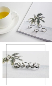 Detailed close-up of five vintage silver-plated rings with intricate floral and woven texture