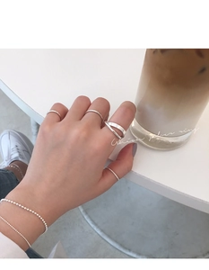 Macro shot of minimalist S925 silver overlapping rings and bracelet on a white table