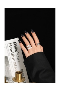 Detail of silver S925 minimalist crossover ring with irregular hollow texture on finger
