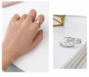 Stacked S925 sterling silver rings and bead bracelet displayed on a hand and magazine