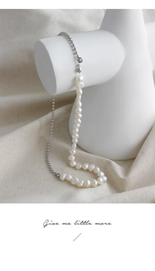 Collana con perle barocche e sfere d'argento su un supporto geometrico bianco