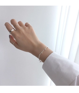 Close-up of minimalist S925 sterling silver rings and bead bracelet on a model wrist