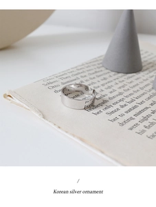 Détail macro d'une bague large argentée avec gravure posée sur un livre ouvert