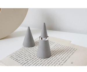 Détail d'une bague large en argent S925 poli sur un support conique gris minimal
