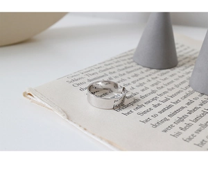 Gros plan sur une bague argentée ajustable à texture brossée et lettres gravées