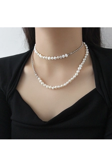 Primo piano di una collana a due strati con perle barocche e sfere d'argento su modella