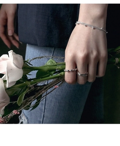 Close-up of elegant S925 silver double-loop rings and beaded chain with pink roses