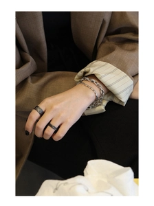 Detail of vintage silver chain bracelet and oxidized ring on a model in a suit
