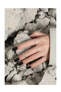 Primer plano de anillos minimalistas de plata esterlina S925 en manos con piedras oscuras
