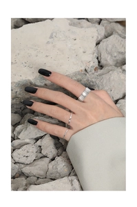 Detalle de anillos texturizados de plata S925 usados por una modelo sobre piedra gris