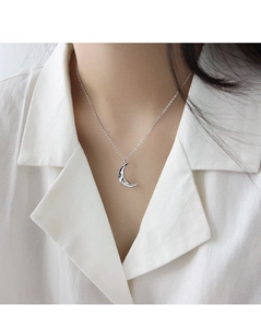 Primo piano di una collana minimalista con ciondolo a luna in argento sulla clavicola