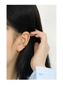 Detail van s925 zilveren clip-on oorbellen met gladde en gehamerde gouden texturen