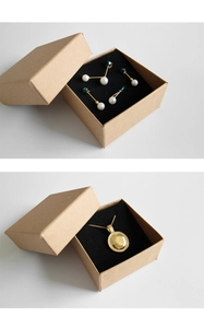 Detail van kraftpapieren juwelendoos met pareloorbellen en gouden hanger ketting