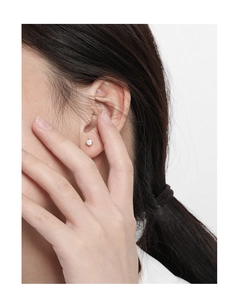 Primer plano de pendientes minimalistas de plata S925 con circón de cuatro puntas