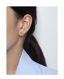Gros plan d'une boucle d'oreille pépite dorée minimaliste portée par un mannequin