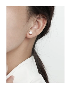 Primer plano de pendiente minimalista de plata S925 con circón en la oreja del modelo