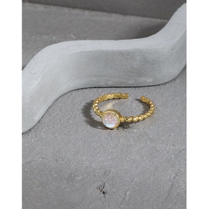 Verstellbarer goldener Seilring mit rundem schillerndem Mondstein auf minimalistischem Grau