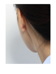 Gros plan d'une puce d'oreille minimaliste en argent s925 en forme de bille sur le lobe