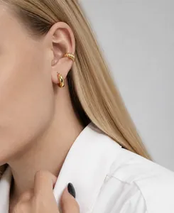 Primer plano de una modelo con pendientes de aro y ear cuff de plata S925 dorada