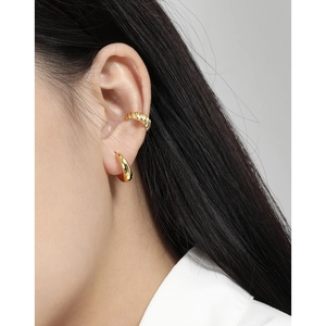 Pendientes de aro S925 y brazalete dorado minimalistas lucidos por una modelo femenina
