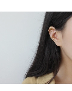 Dettaglio di quattro ear cuff dorati minimalisti con design a treccia e strati multipli