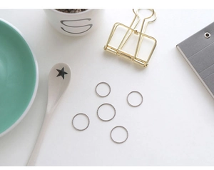 Top view of five minimalist silver twisted rope rings on a clean white aesthetic tabletop