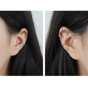 Dettaglio di ear cuff intrecciati oro e argento a doppio strato per orecchie senza buco