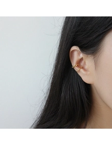 Primo piano di ear cuff dorati a doppio strato con trama a catena e design ad arco liscio
