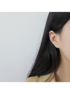 Dettaglio del set di ear cuff dorati con design a doppia linea e trama a treccia