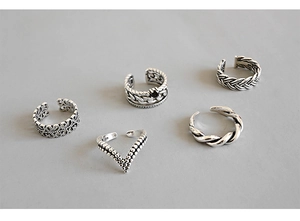 Macro shot of five vintage S925 silver adjustable rings with floral and braided patterns